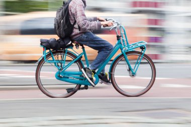 motion blur image of a young man with a bicycle on the move in the city