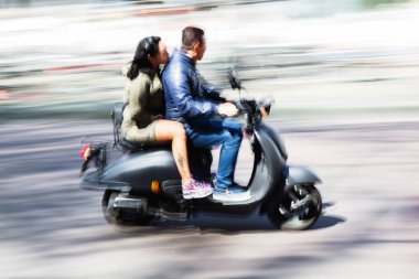 picture in intentional motion blur of a couple on a scooter driving in the city