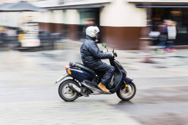 picture in intentional motion blur of a man with a scooter driving in the city