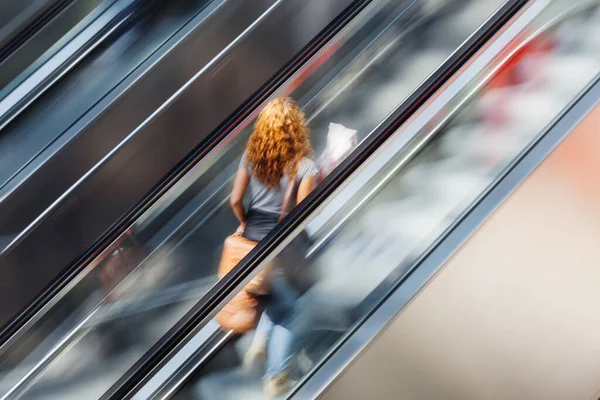 Foto Uma Mulher Uma Escada Rolante Com Efeito Borrão Movimento — Fotografia de Stock