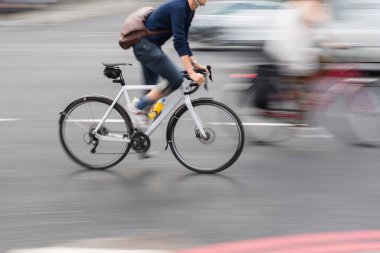 Şehir trafiğinde bisiklet süren bir adamın kasıtlı hareket bulanıklığı etkisi.