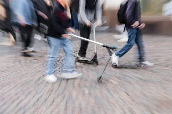 混雑した街の歩行者エリアにキックスクーターを持つ若者のズーム効果で写真 — ストック写真
