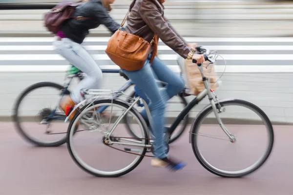 图上的年轻女子与购物袋骑自行车在城市街道上的故意动作模糊 — 图库照片