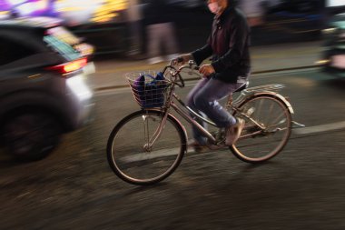 Gece şehir trafiğinde bisikletli bir adamın hareket bulanıklığı efekti.