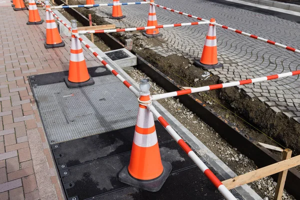 Trafik konileri ve uyarı bandı olan bir yol inşaatının resmi
