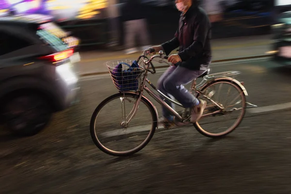一个骑自行车的男子夜晚在城市交通中的动作效果模糊的图片 — 图库照片