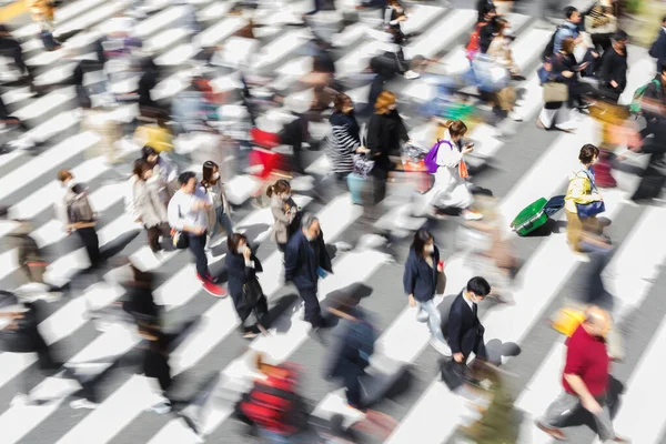 東京のゼブラ交差点で街の通りを横断している人々の群衆の意図的な動きのブラーで写真 — ストック写真