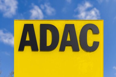 Münih, Almanya - 5 Nisan 2023: ADAC logosu mavi gökyüzüne karşı. ADAC 'ın amacı, yaklaşık 21 milyon üyesi bulunan otomobil, motor sporu ve turizm çıkarlarının temsil edilmesi, desteklenmesi ve savunulmasıdır.