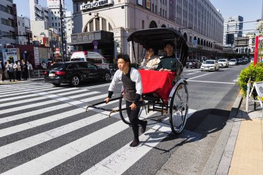Tokyo, Japonya - Nisan 09: Kimliği belirsiz bir adam Tokyo, Japonya sokaklarında iki yolcuyla triportör çekiyor. Tokyo Japonya 'nın başkenti ve en kalabalık vilayetidir.