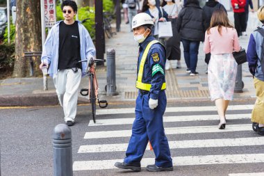 Tokyo, Japonya - 08 Nisan 2023: Tokyo şehir merkezindeki trafik polisi ve diğer kimliği belirsiz kişiler Japonya 'nın en kalabalık ve başkentidir.
