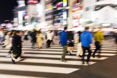 Tokyo, Japonya 'da gece vakti bir caddeyi geçen kalabalığın hareket bulanıklığı yaratmış.