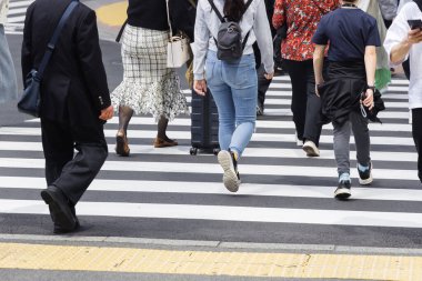 Tokyo, Japonya 'da bir şehir caddesini geçen kalabalığın resmi.