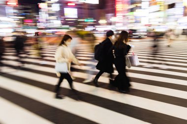 Tokyo, Japonya 'da gece vakti bir şehir caddesinden geçen kalabalığın kasıtlı hareket bulanıklığı
