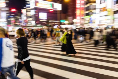 Tokyo, Japonya 'da gece vakti bir şehir caddesinden geçen kalabalığın kasıtlı hareket bulanıklığı
