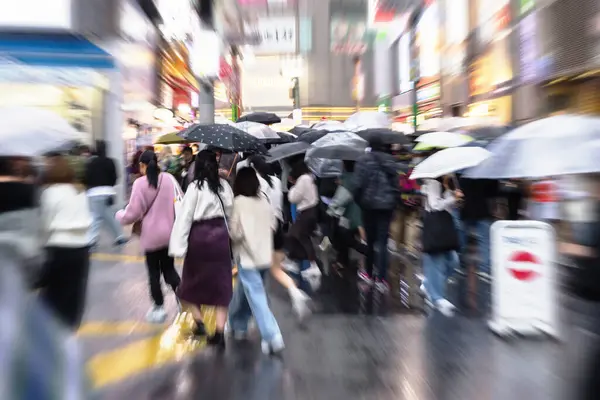 crowds of people with umbrellas on the move in Shibuya district in Tokyo, Japan, while it is raining
