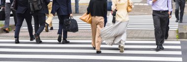 İş adamları Tokyo, Japonya 'daki zebra geçidinde bir şehir caddesini geçiyorlar.