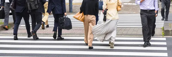 business people crossing a city street at the zebra crossing in Tokyo, Japan