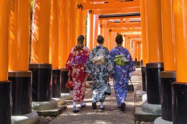 Kyoto, Japonya - 17 Nisan 2023: Kimono 'da üç Avrupalı kadın Fushimi Inari-Taisha Tapınağı' ndaki Torii yolunda yürüyorlar.