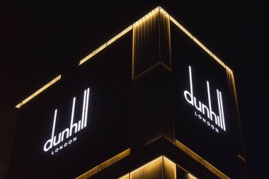 Osaka, Japonya - 13 Nisan 2023: Dunhill London logosuyla aydınlatılmış cephe gece. Alfred Dunhill Limited bir İngiliz lüks mal markası.