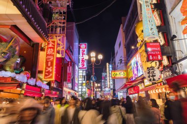 Osaka, Japonya - 13 Nisan 2023: Dotonbori bölgesinde gece vakti, kimliği belirsiz insanlarla alışveriş caddesi. Başlıca turist ve gece hayatı bölgelerinden biri olarak bilinen bölge, Dotonbori kanalı boyunca uzanır.