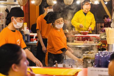 Osaka, Japonya - 13 Nisan 2023: Dotonbori bölgesindeki bir sokak mutfağında, kimliği belirsiz insanlarla birlikte. Dotonbori, Osakas 'ın başlıca turist ve gece hayatı bölgelerinden biri olarak biliniyordu..