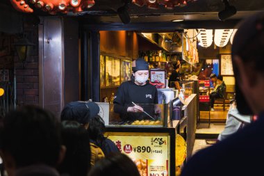 Osaka, Japonya - 13 Nisan 2023: Dotonbori bölgesindeki bir sokak mutfağında, kimliği belirsiz insanlarla birlikte. Dotonbori, Osakas 'ın başlıca turist ve gece hayatı bölgelerinden biri olarak biliniyordu..