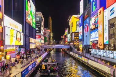 Osaka, Japonya - 13 Nisan 2023: Dotonbori Kanalı 'nda gece. Osaka 'nın başlıca turistik ve gece hayatı alanlarından biri olarak bilinen bölge, Dotonbori kanalı boyunca uzanır.