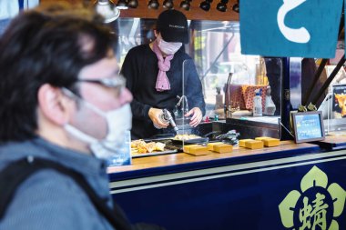 Tokyo, Japonya - 12 Nisan 2023: Kimliği belirsiz insanlarla Tsukiji Balık Pazarı 'ndaki sokak yemekleri tezgahı. Bu büyük bir turistik ilgi odağı. 2018 'den önce dünyanın en büyük balık pazarıydı.