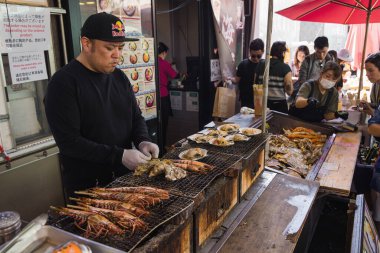 Tokyo, Japonya - 12 Nisan 2023: Kimliği belirsiz insanlarla Tsukiji Balık Pazarı 'ndaki sokak yemekleri tezgahı. Bu büyük bir turistik ilgi odağı. 2018 'den önce dünyanın en büyük balık pazarıydı.