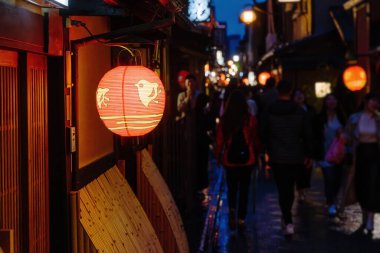 Geceleri Kyoto 'nun eski kasabasındaki Ponto-cho bölgesinde ön planda bir Japon fenerine odaklanmış bir sokak.