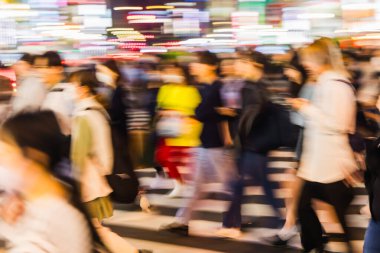Büyük şehirde gece vakti caddeyi geçen bir kalabalığın soyut fotoğrafı.