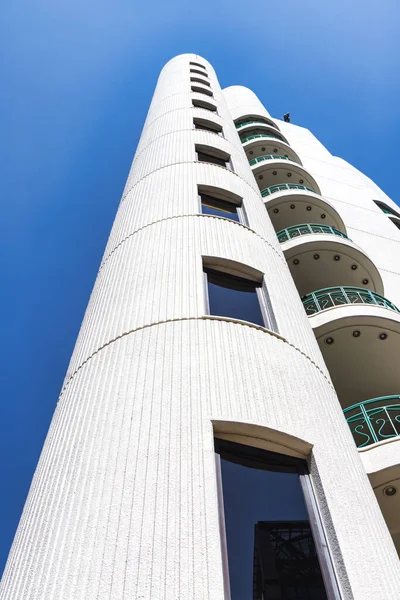 image of a unique residential building in Tokyo, Japan, in a low angle view, with clear blue sky