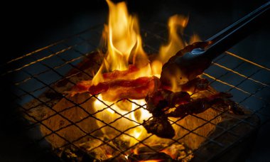 making grill pork outdoor party with fire from coal on iron net and keeper in asian food party