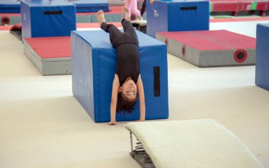 Genç Asyalı jimnastikçi beden eğitimi için spor aletleriyle amuda kalkıyor. 