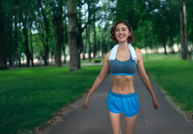 Mutlu Asyalı kız sabah temiz hava almak için parkta yürüyor. 