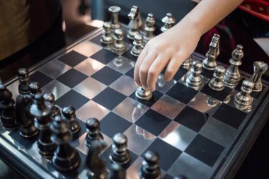 A hand reaching for a chess pawn, about to start a new game