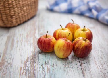 Yıpranmış ahşap bir masada duran bir çiftlikten taze elma topladım. Elmaların ve masanın doğal güzelliğini ve dokusunu yakalayın. Organik ve sağlıklı hissi vurgulayın..