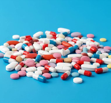 Canlı mavi bir arka plana saçılmış ilaç hapları, sağlık, sağlık ve reklam kampanyaları için mükemmel.