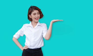 Avuç içi jesti olan Asyalı bir model, kamera dışındaki bir ürüne dikkatle odaklanıyor. Reklamlar için ideal, dikkat çekmek ve potansiyel müşterileri davet etmek için.