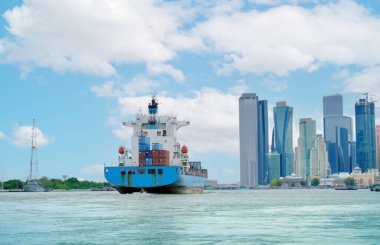 Hareketli kargo teknesi şehre doğru süzülür, canlı bir su yolu boyunca mal taşır.