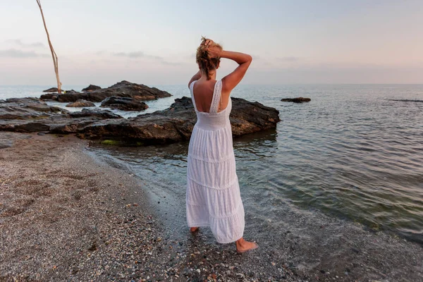 beautiful woman over 50 years old on the beach with a white dress