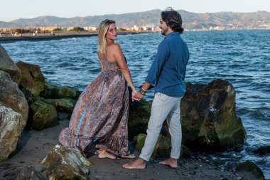 Genç çift arka planda denize poz veriyor.