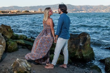 Genç çift arka planda denize poz veriyor.