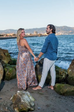 Genç çift arka planda denize poz veriyor.