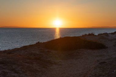 Deniz kenarında kırmızı renklerle gün batımının harika bir fotoğrafı.