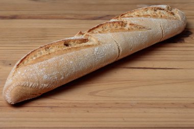 Tahta bir masanın üstünde duran taze pişmiş ekmek somunu.