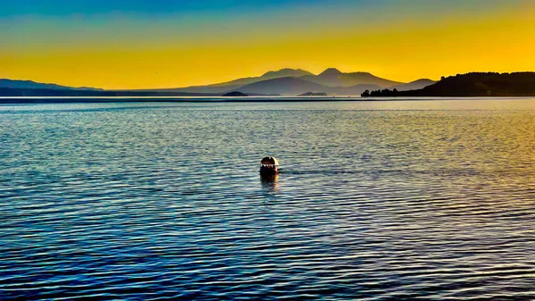 中央高原の3つの火山の壮大な色の背景を持つ夕暮れ時にTaupo湖を航海する — ストック写真