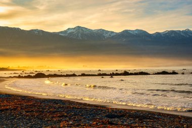 Kaikoura Körfezi öğleden sonra ılık güneş ışığıyla aydınlandı. Arka planda karlı dağlar vardı.