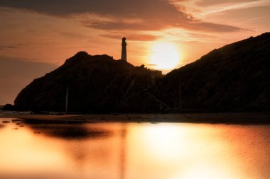 Castlepoint lighthouse at sunrise creating a silhouette of the rock and lighthouse