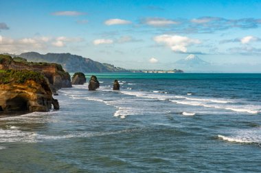 Tongaporutu sahilindeki üç kız kardeş olarak bilinen kaya oluşumları Taranaki kıyı şeridindeki yüksek gelgitte.